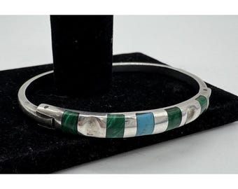 May include: A silver-toned hinged bangle bracelet featuring alternating rectangular inlays of dark green malachite and a single light blue turquoise stone. The metal band has a smooth, polished finish with a secure clasp mechanism on one side.