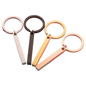 Peut inclure: Quatre porte-clés en métal avec un charme en forme de barre. Les porte-clés sont en or rose, or, argent et noir.