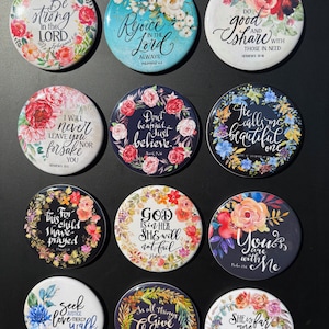 Peut inclure: Ensemble de magnets ronds avec des motifs floraux et des citations inspirantes. Chaque aimant présente un design différent, avec des fleurs colorées et des phrases comme "Don't be afraid, just believe" et "Give Thanks".