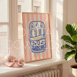 May include: A framed art print featuring a blue and white illustration of sardines in a can against a pink and white striped background. The print has the words "DIGITAL DOWNLOAD" in white. The frame is a light brown color.