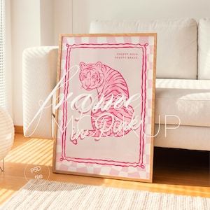 Könnte beinhalten: Gerahmter Kunstdruck mit einer rosa Tiger-Illustration. Das Kunstwerk hat einen karierten Rand und den Text "PREPPY BOLD, PREPPY BRAVE." Der Rahmen ist aus hellem Holz.