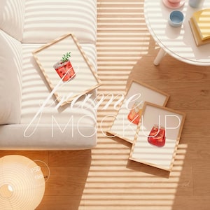 May include: Wooden framed art prints featuring watercolor illustrations of refreshing beverages. The prints are displayed on a light-colored sofa and wooden floor, with the text "frame mockup" overlaid on the image.