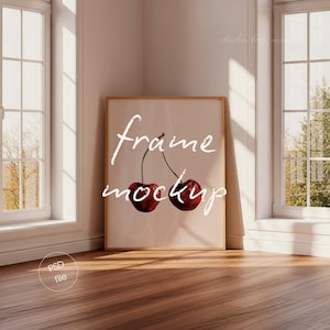 May include: A framed art print featuring two cherries with stems, in a light-filled room. The words "frame mockup" are written in white script across the image. The room has two windows and a wooden floor.