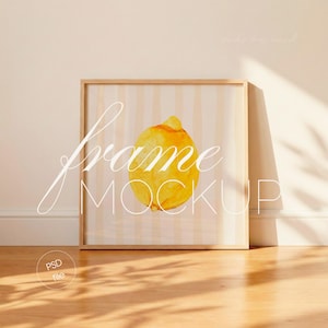 Könnte beinhalten: Ein gerahmter Kunstdruck mit einer Aquarell-Zitronen-Illustration. Das Kunstwerk hat einen hellbeige-weiß gestreiften Hintergrund. Der Rahmen ist hellbraun. Die Worte "frame mockup" sind auf dem Kunstwerk geschrieben. Das Bild befindet sich auf einem Holzboden.
