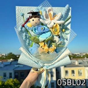 Crochet graduation bouquet in blue and white shades with crochet daisies and delicate leaves.
