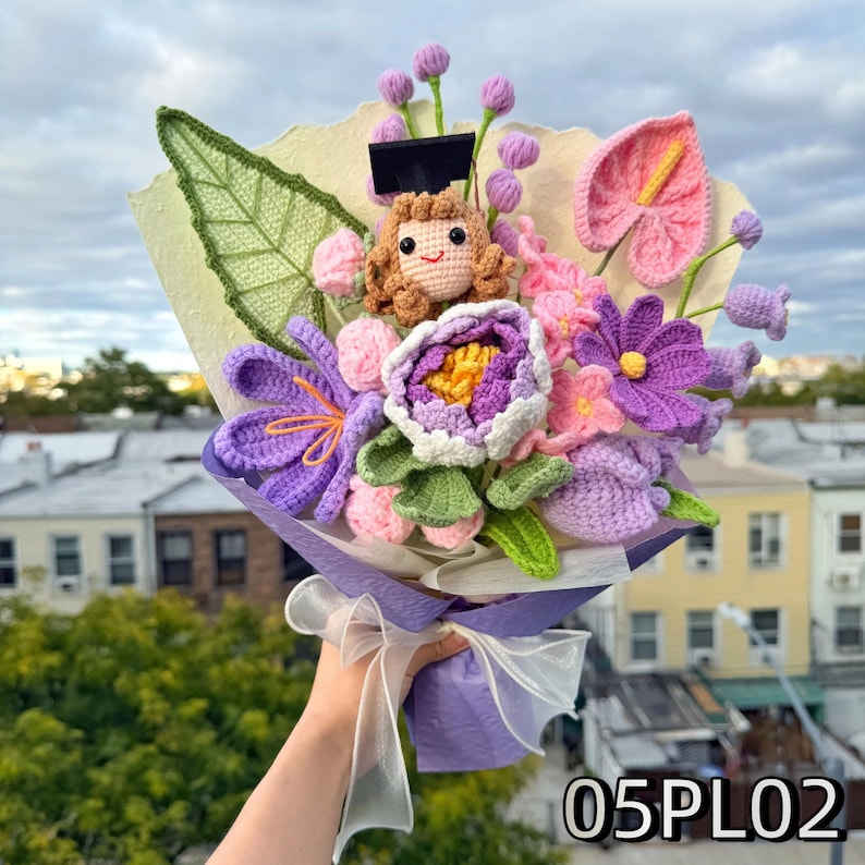 Crochet graduation bouquet in lilac and violet tones with layered crochet blooms and green leaves.