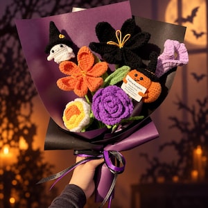 May include: A crochet flower bouquet wrapped in purple and black paper, featuring a white ghost in a black witch hat, an orange flower, a yellow and white flower, a black flower, a purple rose, and an orange pumpkin with a black hat.