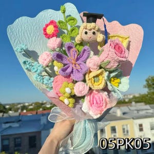 Crochet graduation bouquet in pink and yellow tones with layered crochet flowers and greenery.