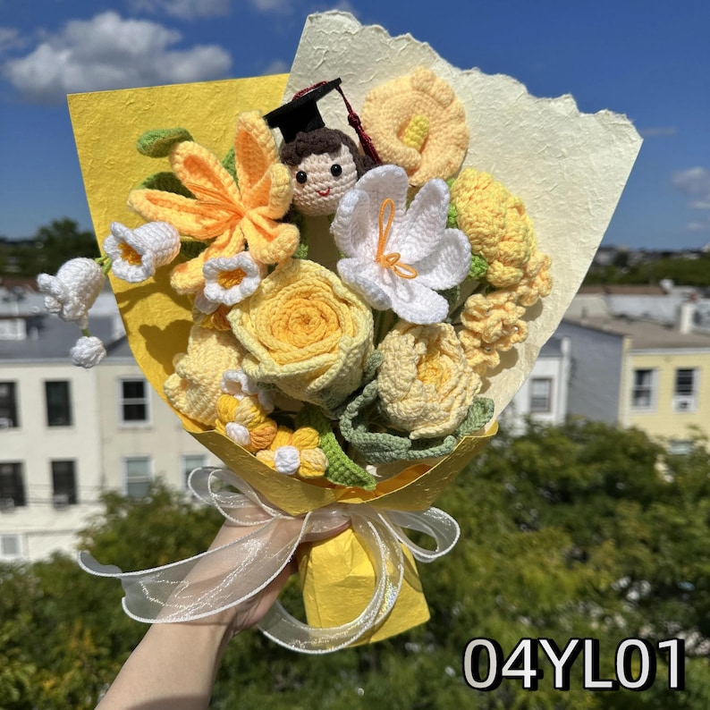 Crochet graduation bouquet in warm yellow and white tones with crochet roses and daisies, wrapped in light cream paper.
