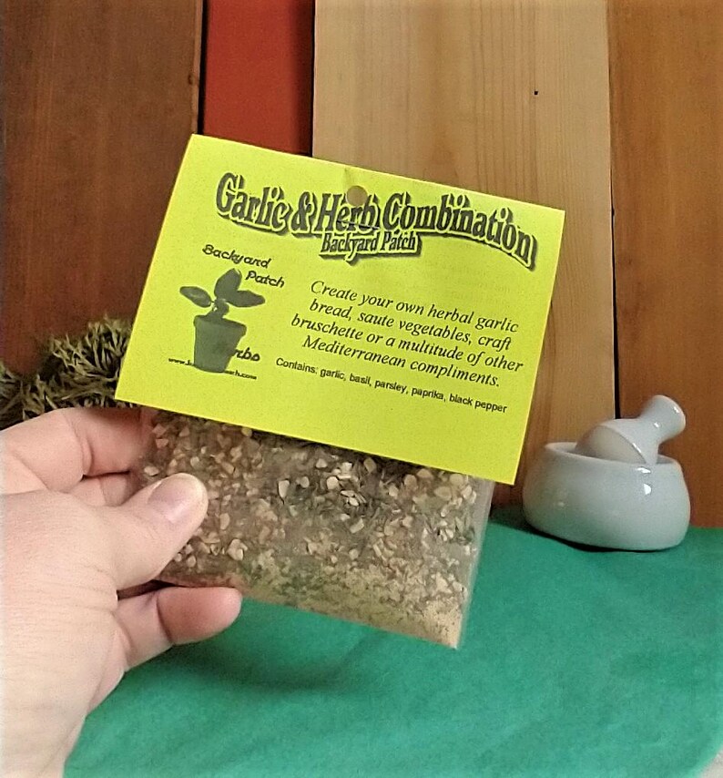 Peut inclure: Un sachet jaune et vert d'herbes et d'&eacute;pices s&eacute;ch&eacute;es &eacute;tiquet&eacute; "Garlic & Herb Combination Backyard Patch". L'&eacute;tiquette comprend &eacute;galement le texte "Create your own herbal garlic bread, saute vegetables, craft bruschette or a multitude of other Mediterranean compliments. Contains: garlic, basil, parsley, paprika, black pepper."