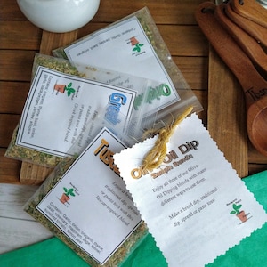May include: Three small bags of dried herbs labeled "Tuscan", "Greek", and "Rosemary" with a white card that reads "Oil Dip Sample Bundle" and "Enjoy all three of our Olive Oil Dipping blends with many different ways to use them. Make a bread dip, traditional dip, spread or pasta toss!"