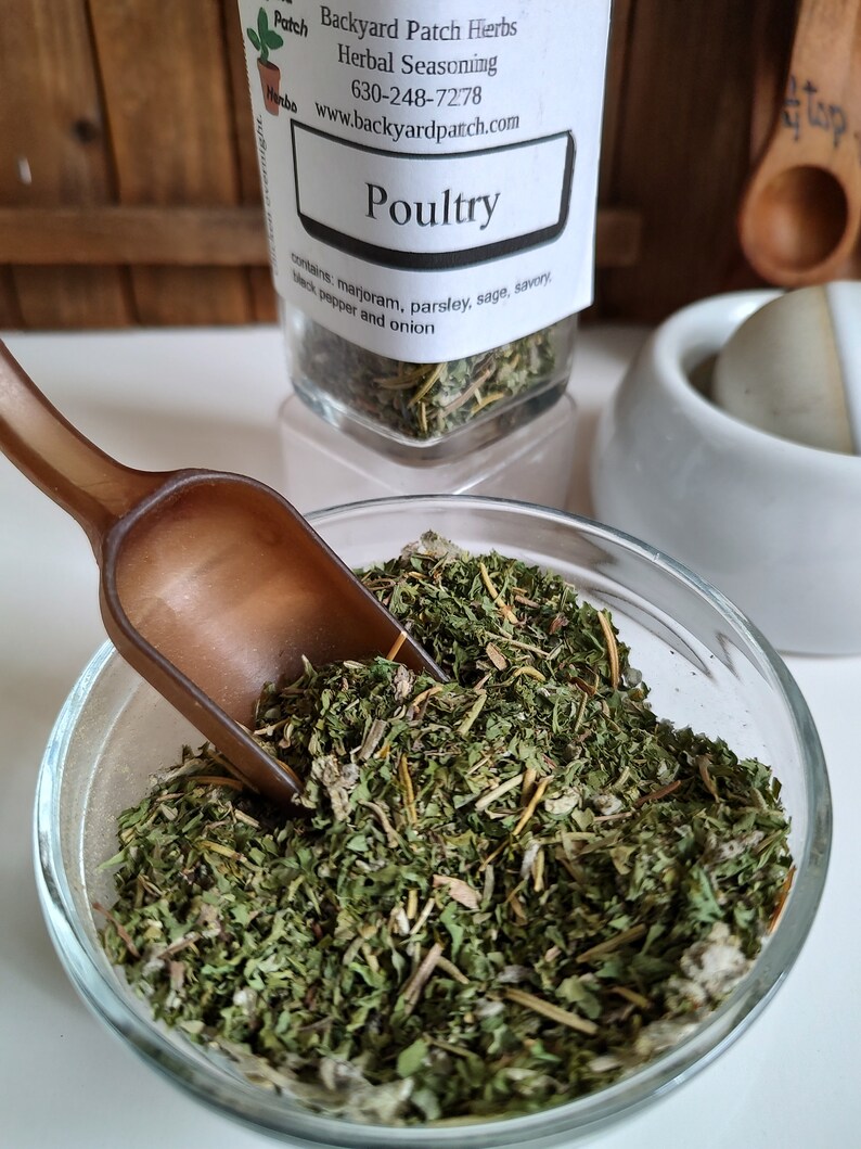Pu&ograve; includere: Un barattolo di vetro pieno di erbe secche etichettato "Poultry" con il testo "Backyard Patch Herbs Herbal Seasoning 630-248-7278 www.backyardpatch.com" e "contains marjoram, parsley, sage, savory, black pepper and onion".