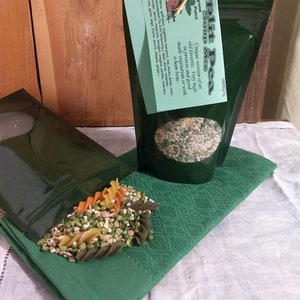 May include: A green resealable bag filled with a split pea soup mix. The bag is labeled "Split Pea Soup Mix" and "Backyard Patch". The text on the label describes the soup mix as a unique version of an old favorite, very high in protein and good made vegetarian or with a ham bone. The soup mix contains split peas, vegetable macaroni, rice, barley, lentils, onion, and a blend of herbs and spices.