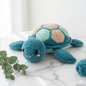 Könnte beinhalten: Eine handgefertigte Häkelschildkröte in Türkis, Beige und Mintgrün. Die Schildkröte hat einen runden Kopf mit schwarzen Sicherheitsaugen und einem rosa gestickten Lächeln. Der Panzer ist im Patchwork-Design gehalten. Neben der Schildkröte liegt ein Knäuel türkisfarbener Wolle.