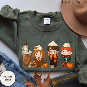 Könnte beinhalten: Militärgrünes Sweatshirt mit Comicfiguren als Kaffeegetränke, garniert mit Schlagsahne und Kürbissen. Das Sweatshirt hat oben den Text "Hello Gifty Co.".