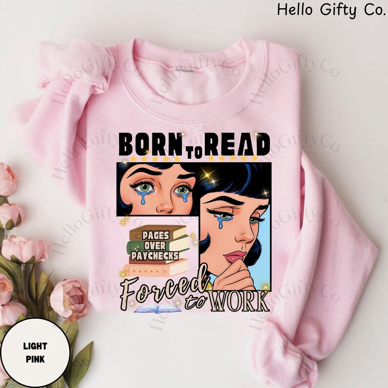May include: Light pink sweatshirt with the text "BORN TO READ" above a graphic of a crying woman. Below the graphic are the words "PAGES OVER PAYCHECKS" and "FORCED TO WORK".