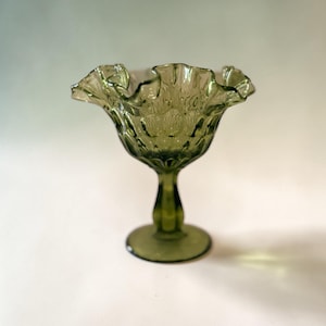 Puede incluir: Una taza de cerámica blanca con un asa negra y el texto "But First, Coffee" en negro y negrita. La taza está sobre una superficie blanca.