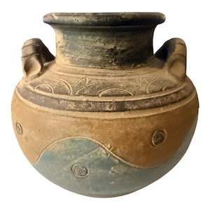 May include: A round ceramic vessel with two side handles, featuring a wide neck and a textured surface. The body displays a color palette of muted tan and blue-grey, decorated with embossed circular patterns and curved lines around the shoulder.