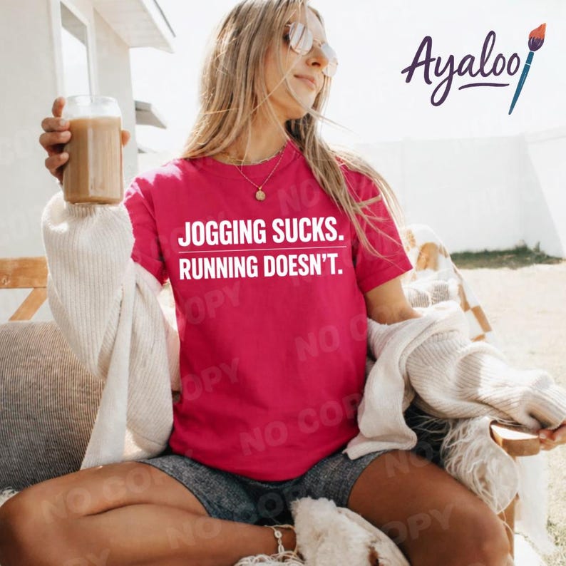 Puede incluir: Una camiseta magenta con el texto "JOGGING SUCKS. RUNNING DOESN'T." en blanco. La persona que lleva la camiseta sostiene un vaso de una bebida marr&oacute;n. La persona tambi&eacute;n lleva gafas de sol y pantalones cortos.