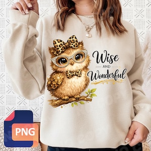 May include: Beige sweatshirt featuring a cartoon owl with glasses, a bow, and a bow tie. The owl is perched on a branch with green leaves. The text "Wise and Wonderful" is written on the sweatshirt.