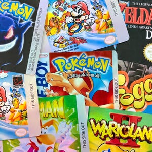 May include: A selection of retro Game Boy game boxes, including Pokémon, Mario, and Zelda titles. The boxes are adorned with vibrant graphics and text, with the "Pokémon" box in focus. The image evokes a sense of classic video game nostalgia.