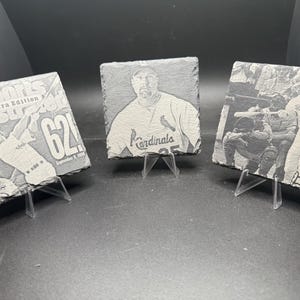 May include: Three slate coasters with baseball-themed images. One features a Sports Illustrated cover with "62!" and the date. Another shows a Cardinals player. The third depicts a baseball game scene.