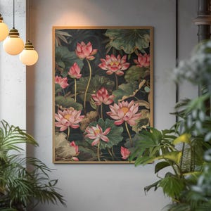 May include: A framed art print featuring a botanical illustration of pink lotus flowers and green leaves against a dark background. The artwork is displayed in a room with hanging lights and plants.