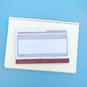 May include: A lined notepad within a spiral-bound notebook, featuring a design mimicking a website comment section. The notepad has a white background with grey and red details. The text "Comment as" is displayed on the notepad.