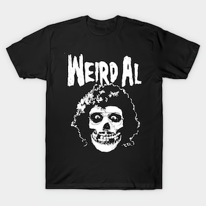 May include: Black t-shirt featuring a white graphic of a skull wearing glasses and curly hair, with the text "Weird Al" above the skull. The design has a distressed, vintage look.