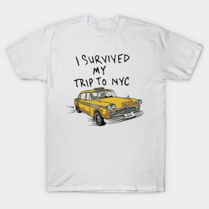 Könnte beinhalten: Weißes T-Shirt mit einer Cartoon-Illustration eines gelben New Yorker Taxis. Der Text "I Survived My Trip To NYC" ist über dem Taxi aufgedruckt. Das Taxi hat einen Fahrer mit einem Smiley-Gesicht. Casual Wear.