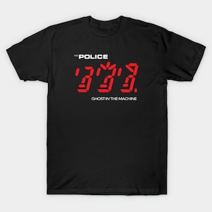 May include: Black t-shirt featuring the text "THE POLICE" above a red digital display of the number "333". Below the number is the text "GHOST IN THE MACHINE". The shirt is a classic crew neck style.
