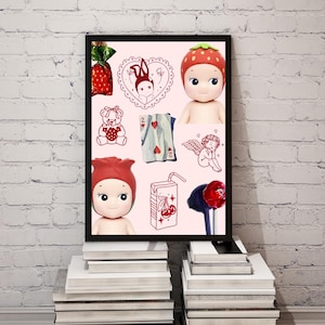 May include: A framed print featuring a collection of whimsical illustrations and figurines. The artwork includes a strawberry-themed doll, a teddy bear, playing cards, and a cherub. The color palette is soft, with pink and red accents.