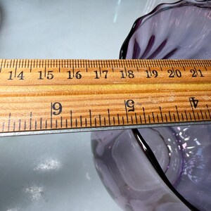 Peut inclure: Un bol en verre violet clair avec un bord festonn&eacute;. Le bol est mesur&eacute; avec une r&egrave;gle en bois. Le diam&egrave;tre du bol est d'environ 12,7 cm.