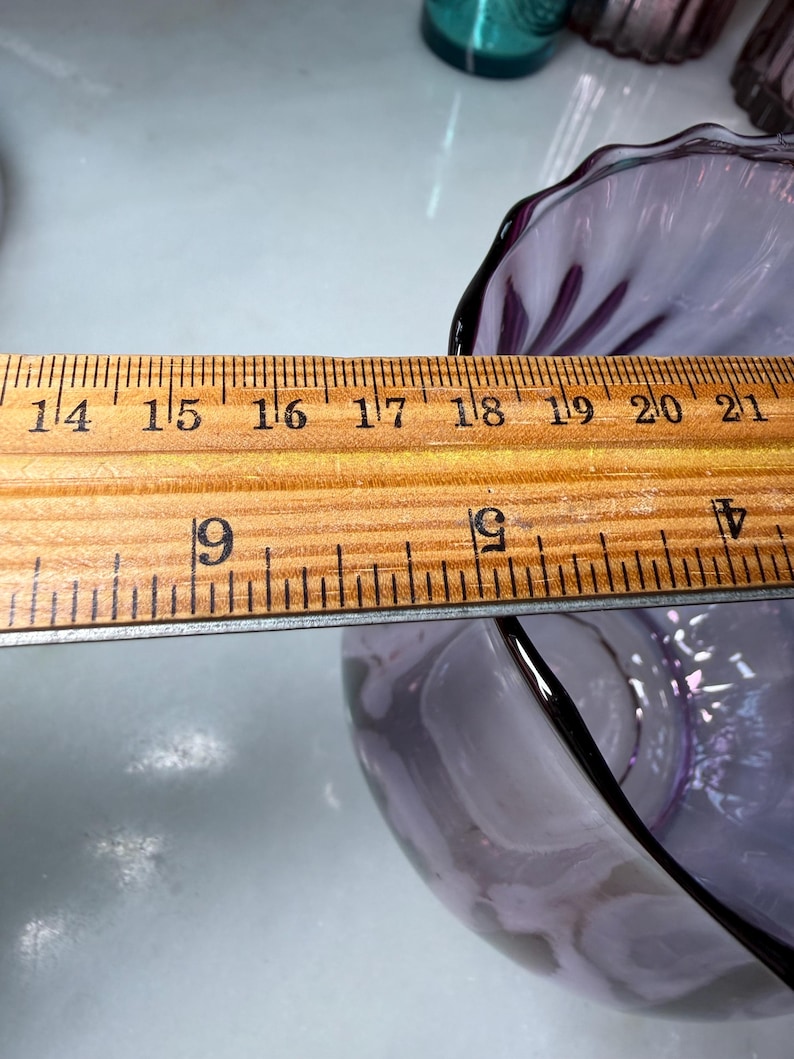 Peut inclure: Un bol en verre violet clair avec un bord festonn&eacute;. Le bol est mesur&eacute; avec une r&egrave;gle en bois. Le diam&egrave;tre du bol est d'environ 12,7 cm.