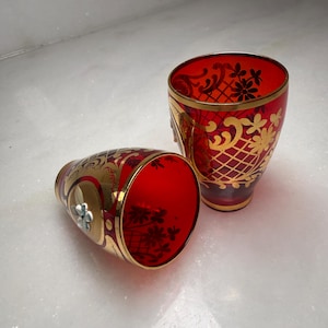 May include: A white ceramic mug with a black handle and the text "But First, Coffee" in a black, handwritten-style font. The mug is on a white surface.