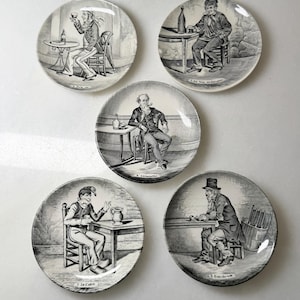 May include: Set of five vintage porcelain plates with black and white illustrations of men in a tavern setting. Each plate features a different scene with a man seated at a table, drinking or smoking.