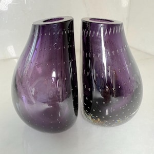 Peut inclure: Deux vases en verre violet en forme de goutte d'eau présentant une technique bullicante distincte avec de petites bulles d'air régulièrement espacées emprisonnées dans les parois en verre épais. Chaque vase a une finition lisse et polie.