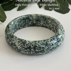 May include: A natural jade bangle with deep forest green and white marbling, featuring the text Natural Jade Bangle, Deep Forest Green | White Marbling | 60.5 mm, and AmorGemsBoutique at the bottom. The bangle has a smooth, polished surface.