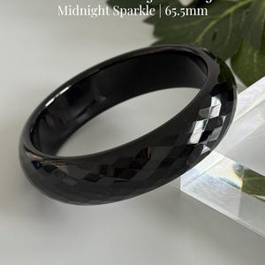 May include: A faceted black crystal bangle with a glossy finish and a diamond-cut pattern. The text on the image reads: Faceted Black Crystal Bangle, Midnight Sparkle | 65.5mm, and AmorGemsBoutique. The bangle has an inner diameter of 65.5mm.