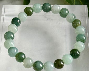 Può includere: Un braccialetto di giada con perline rotonde e lucide in varie tonalità di verde. Il testo sull'immagine recita "Certified Grade A Jadeite Mint Moss Tricolor | 8.7 mm". Le perline misurano circa 0,87 cm di diametro.
