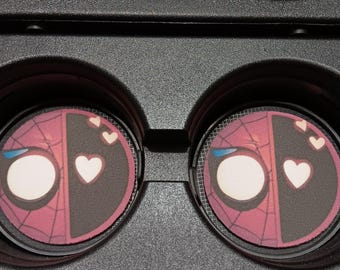May include: Two car coasters featuring a split design: one side depicts Spider-Man's mask, the other Deadpool's mask. Each coaster has a white heart and two smaller hearts. The coasters are set in a black car console.