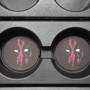 Può includere: Una custodia nera contenente due paia di lenti rotonde e due inserti circolari con il design della maschera di Deadpool. Le lenti hanno un motivo a rete. Gli inserti di Deadpool sono neri con una maschera rossa e bianca.