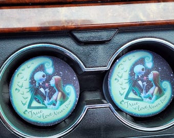 May include: Two car coasters featuring a romantic illustration of Jack Skellington and Sally from The Nightmare Before Christmas. The coasters are round with a starry background and the text "True Love Never Dies".