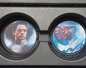 May include: A close-up of a black tray with circular compartments. Two compartments contain images of characters from a superhero franchise. One features a man with short hair, and the other shows a man wearing a mask.