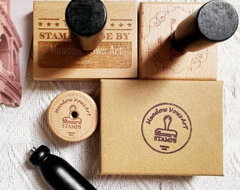May include: A selection of wooden stamps with black handles and a brown cardboard box. The stamps are engraved with the text "STAMPS MADE BY Meadow Vows Art". The stamps are in various shapes and sizes.