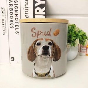 Peut inclure: Un récipient cylindrique en céramique gris clair avec un couvercle en bois. Il présente un portrait peint d'un chien beagle avec le nom "Spud" et une illustration de pomme de terre. Parfait pour la cuisine.
