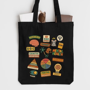May include: Black tote bag featuring colorful illustrations related to psychology and mental health. The design includes images of a brain, a mouse, a dog, and text such as "Therapy", "Mental Health", and "Positive Psychology".