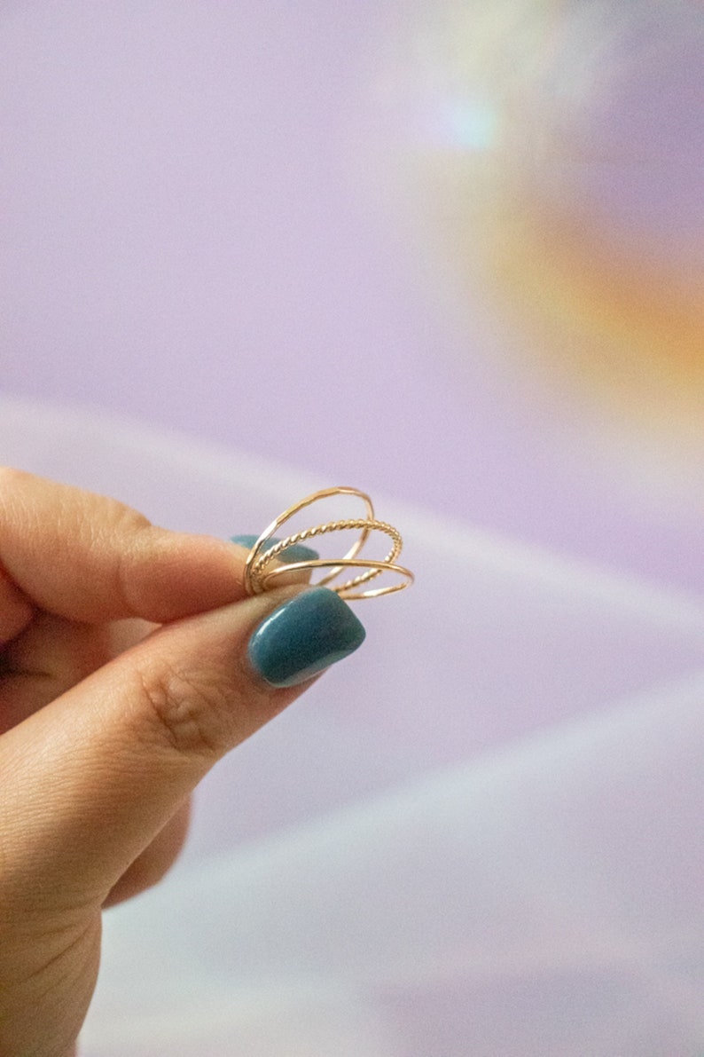 Puede incluir: Un conjunto de cuatro anillos apilables de color dorado. Los anillos son finos y delicados, con un dise&ntilde;o trenzado.
