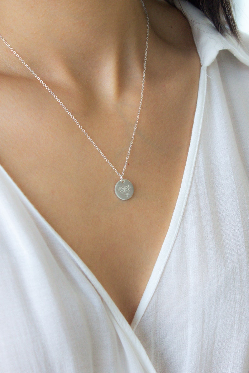 May include: A silver chain necklace with a small, round pendant featuring a delicate floral design.