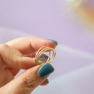 Puede incluir: Un conjunto de tres anillos finos de oro apilados en un dedo. Los anillos est&aacute;n hechos de alambre trenzado y tienen un dise&ntilde;o delicado y minimalista.